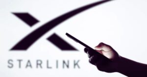 Hand holding smartphone in front of Starlink logo, representing satellite internet launch in Pakistan.